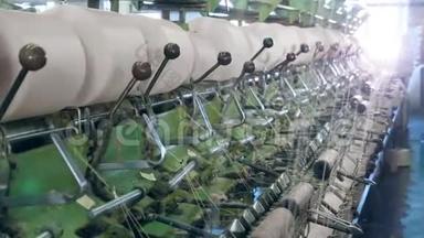 金属机器在一<strong>家纺</strong>织厂与螺纹一起工作，把它们卷到筒管上。